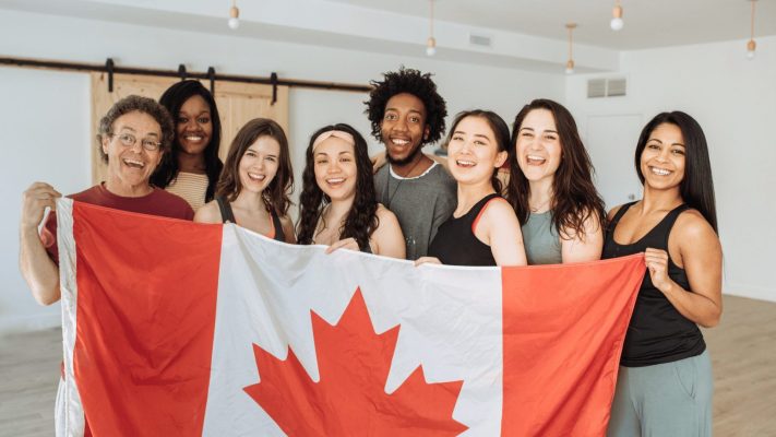 Grupo de estudiantes con la bandera de Canadá al viajar a Canadá